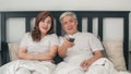 Asian elderly couple watching television in bedroom at home, Asia couple enjoy love moment while lying on the bed when relaxed at Royalty Free Stock Photo