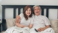 Asian elderly couple watching television in bedroom at home, Asia couple enjoy love moment while lying on the bed when relaxed at Royalty Free Stock Photo