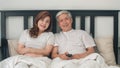 Asian elderly couple watching television in bedroom at home, Asia couple enjoy love moment while lying on the bed when relaxed at Royalty Free Stock Photo