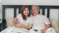 Asian elderly couple watching television in bedroom at home, Asia couple enjoy love moment while lying on the bed when relaxed at Royalty Free Stock Photo