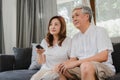 Asian elderly couple watching television in living room at home, sweet couple enjoy love moment while lying on the sofa when Royalty Free Stock Photo