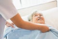 Asian elderly look at her caregiver. nurse putting blanket on senior woman on the bed in the nursing home Royalty Free Stock Photo