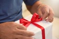 Asian elderly man holding on red ribbon of white gift box. Royalty Free Stock Photo