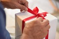 Asian elderly man holding on red ribbon of white gift box. Royalty Free Stock Photo