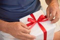 Asian elderly man holding on red ribbon of white gift box. Royalty Free Stock Photo