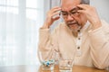 Asian elderly man sick have headache looking pill glass on at home Royalty Free Stock Photo
