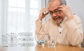 Asian elderly man sick have headache looking pill glass on at home Royalty Free Stock Photo