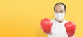 Asian Elderly man wear surgical mask and red boxing gloves is fighting and prevent coronavirus. Senior male boxer exercising