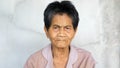 Asian elderly native woman looking to camera with serious face, smiling in eyes isolated concrete grey wall background. Concept of Royalty Free Stock Photo