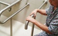 Asian elderly old woman patient use toilet support rail in bathroom, handrail safety grab bar, security in nursing hospital