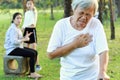 Asian elderly people having heartbeats fast,difficulty breathing,symptoms of heart problem while walking exercise in outdoor park, Royalty Free Stock Photo