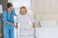 Asian elderly senior woman using walker aid with nurse care support step walking at home Royalty Free Stock Photo