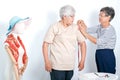 Asian elderly tailor woman show action of body measurement for the other elderly customer near cloth puppet. Image is isolated on