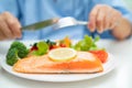 Asian elderly woman patient eating Salmon steak breakfast with vegetable healthy food while sitting and hungry on bed in hospital Royalty Free Stock Photo