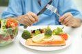 Asian elderly woman patient eating Salmon steak breakfast with vegetable healthy food while sitting and hungry on bed in hospital Royalty Free Stock Photo