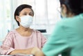 Asian Elderly woman patient wearing protective face mask talking consulting with Female Doctor or Nurse in medical office clinic Royalty Free Stock Photo