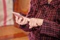 Asian elderly woman sitting and looking through something on modern smartphone, making connection with others at home, living