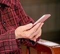 Asian elderly woman sitting and looking through something on modern smartphone, making connection with others at home, living