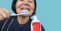 Asian elderly woman trying use toothbrush ,hand tremor . Dental health