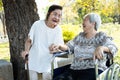 Asian elderly woman with walking stick,enjoy talk to her senior close friend in the wheelchair and laughing together,two old