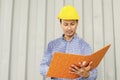 Electrical Engineer holding files while wearing a personal protective equipment safety helmet at construction site. Royalty Free Stock Photo