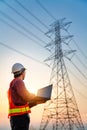 Asian electrical engineers checking location using a notebook computer standing at a power station to view the planning work by