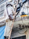 Asian electrician on a ladder repairing wire of the power line on electric power pole Royalty Free Stock Photo