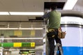 Asian Electrician wiring a ceiling light in subway station