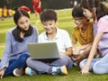 Asian elementary school children using laptop outdoors Royalty Free Stock Photo
