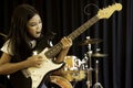 An Asian elementary school girl with long hair playing with serious electric guitar in rock songs. Royalty Free Stock Photo