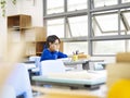 Asian elementary schoolboy sitting alone in classroom Royalty Free Stock Photo