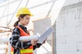 Asian engineer architect worker woman holding blueprint infrastructure progress at construction site Royalty Free Stock Photo