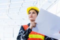 Asian engineer architect worker woman holding blueprint infrastructure progress at construction site Royalty Free Stock Photo