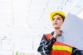 Asian engineer architect worker woman holding blueprint infrastructure progress at construction site Royalty Free Stock Photo