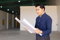 Asian engineer business architect male standing in factory building with floorplan blueprint construction design project Royalty Free Stock Photo