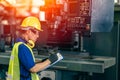 Asian engineer checking the machine in factory, worker writing note with list paper