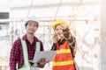 Asian engineer foreman worker man and woman working at building construction site use laptop and talking with radio Royalty Free Stock Photo