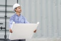 Engineer man with helmet looking paper plans at construction site.