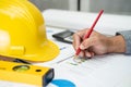 Asian engineer with plan project blueprint, graph and yellow helmet and engineering construction tools