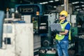 Asian engineer programming the machine in factory with laptop computer to setup program process