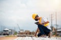 Asian engineer wearing hard hat and safety vest sitting and checking construction problems in construction site Royalty Free Stock Photo
