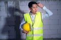 Asian Engineering man with safety helmet feeling Exhausted due to overworking in construction site Royalty Free Stock Photo