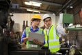 Asian engineering manager and mechanic worker in safety hard hat and reflective cloth using lathe machine in the factory Royalty Free Stock Photo