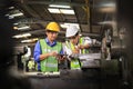 Asian engineering manager and mechanic worker in safety hard hat and reflective cloth using lathe machine in the factory Royalty Free Stock Photo