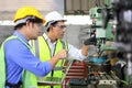 Asian engineering manager and mechanic worker in safety hard hat and reflective cloth using lathe machine in the factory Royalty Free Stock Photo