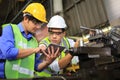 Asian engineering manager and mechanic worker in safety hard hat and reflective cloth using lathe machine in the factory Royalty Free Stock Photo