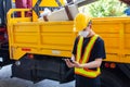 Asian engineering workers with safety equipment standing in front of trucks use tablet to communicate with trucks at construction Royalty Free Stock Photo