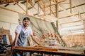 Asian entrepreneur in a hat smiling in a woodcraft workshop