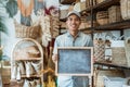 asian entrepreneur holding a blackboard standing in a handicraft shop