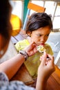 Asian Child Showing Cranky Facial Expression while Being Feed Lunch Meals by His Mother in A Restaurant